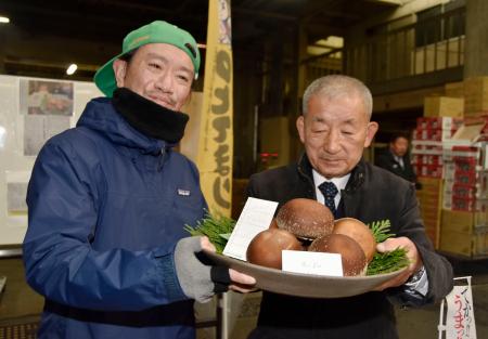 　過去最高額で競り落とされた「のとてまり」を持つ仲買人の浅市佳男さん。右は「奥能登原木しいたけ活性化協議会」の樋下義勝会長＝９日午前、金沢市