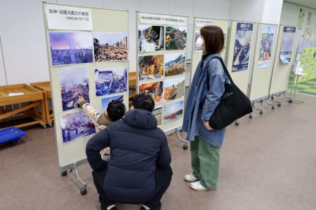 　震災被害を紹介する展示を見る家族連れ＝１１日、東京都練馬区