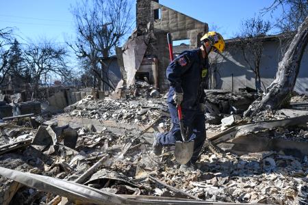 　米ロサンゼルス北部近郊アルタデナで、山火事により焼失した家の跡で不明者を捜索する人＝１３日（ゲッティ＝共同）