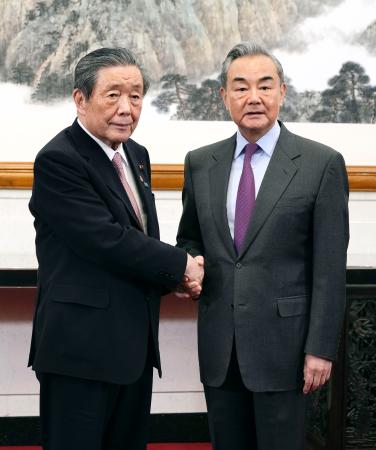 　握手する自民党の森山幹事長（左）と中国の王毅外相＝１４日、北京の釣魚台迎賓館（共同）