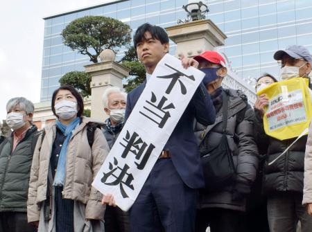 　判決後、「不当判決」と書かれた紙を掲げる原告側代理人（中央）＝１５日午前、神戸市