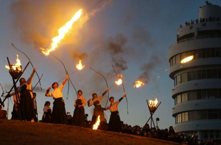 　和歌山県串本町の潮岬で行われた火祭りで、火矢を放つ県立串本古座高の弓道部員たち＝１８日夕