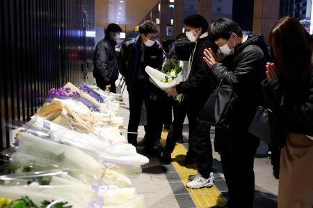 　ＪＲ長野駅前に設置された献花台で手を合わせる人たち＝２３日午後