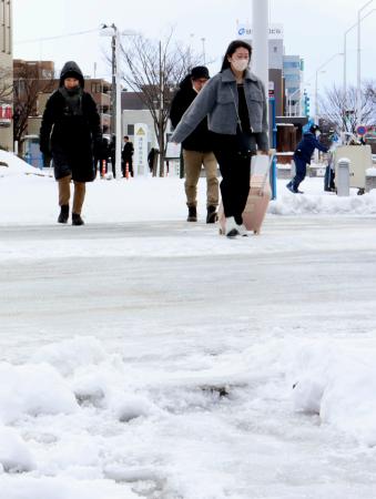 　雪が積もったＪＲ新潟駅前を歩く人たち＝６日午前、新潟市