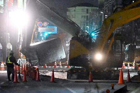 　県道が陥没しトラックが転落した事故で、穴の地表近くにあるコンクリート製の農業用水路の撤去作業を行う重機＝７日午後７時５０分、埼玉県八潮市