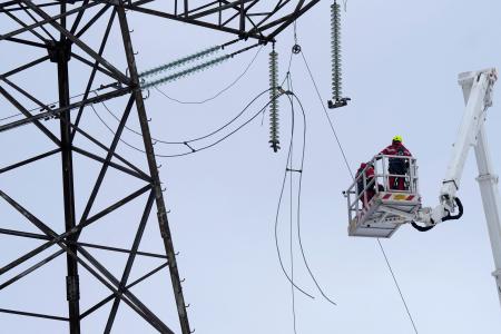 　ラトビア東部ビリャカ近郊で電線を切断する技術者＝８日（ロイター＝共同）