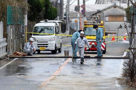 　水道管が破裂し、段差が生じた堺市美原区の市道＝１２日午後０時３９分