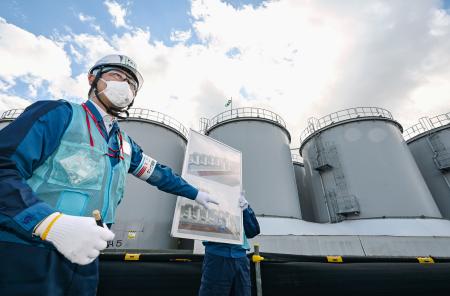 　処理水放出に伴い空になったタンクの前で説明する東京電力の担当者＝１３日、福島第１原発（代表撮影）　