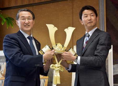 　鳥取県庁で「人形のはなふさ」の英智哉社長（右）から金色のかぶと飾りを受け取る平井伸治知事＝１９日午前