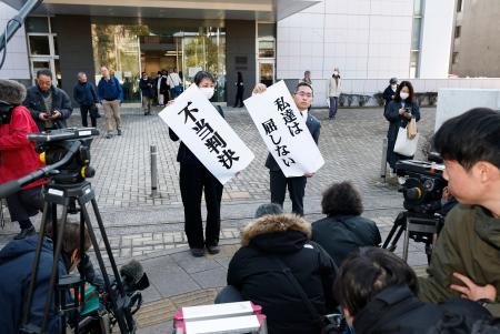 　九州電力川内原発１、２号機の運転差し止めを求めた訴訟の判決を受け、鹿児島地裁前で「不当判決」などと書かれた紙を掲げる原告側＝２１日午後