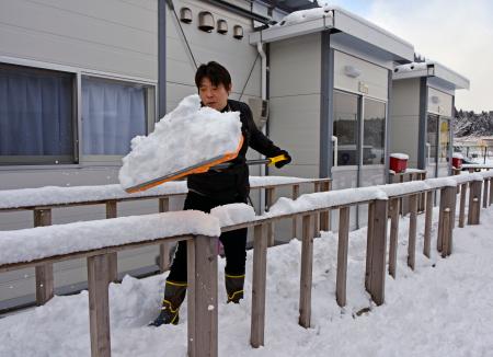 　石川県珠洲市の仮設住宅団地で、雪かきをするボランティア＝２２日午前