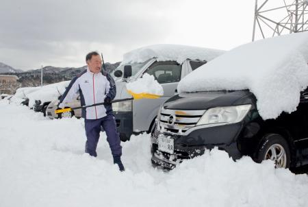 　大雪に見舞われた石川県輪島市で、仮設住宅の駐車場を雪かきする男性＝２２日午前