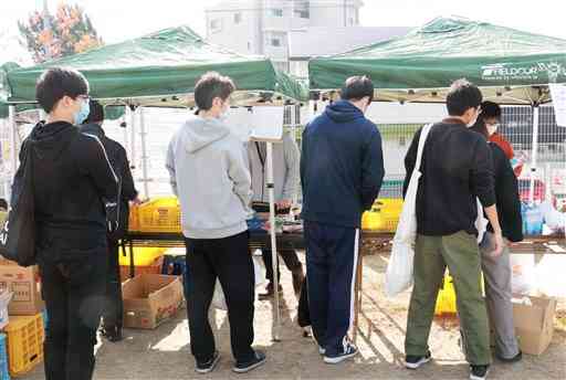 食料の無料配布会の列に並ぶ学生たち＝１３日、熊本市中央区