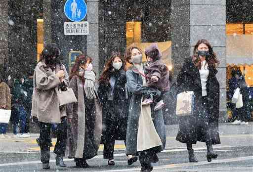 雪が降る通町筋を、厚着をして歩く人たち＝３０日午後３時４５分ごろ、熊本市中央区（池田祐介）