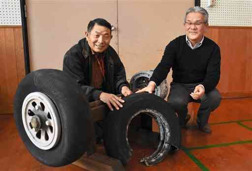 ユングマンのものとみられる軍用機の車輪と所有者の山代成彦さん（左）、右は高谷和生さん＝玉名市
