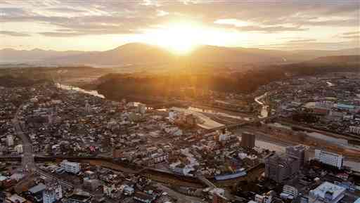 昨年７月の豪雨で被災した人吉市街地に降り注ぐ御来光。中央を横切る球磨川は穏やかに流れていた＝１日午前７時４０分すぎ、同市（高見伸・小野宏明、小型無人機で撮影）