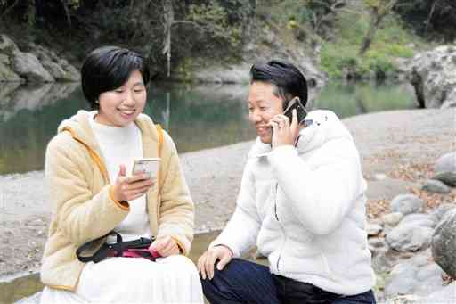 氷川町の立神峽里地公園で、それぞれの仕事をこなす番匠雄一郎さん（右）、麻樹さん夫妻。スマートフォン一つでできるという＝昨年１２月、氷川町