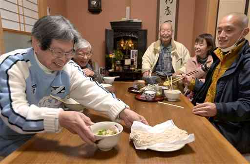 球磨村神瀬の神照寺で年越しそばを食べる住民ら。右は岩崎哲秀住職＝2020年12月３１日、同村（小野宏明）