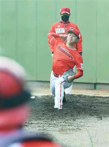 ブルペンで投球練習する佐野太河。後方は馬原孝浩投手ゼネラルマネジャー＝山鹿市民球場