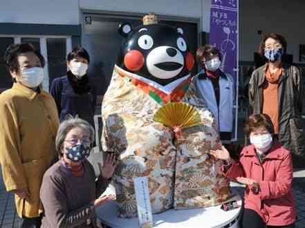 「ひなぐ雛祭り」に合わせ、くまモン像に華やかな着物をまとわせた婦人会のメンバーたち＝八代市