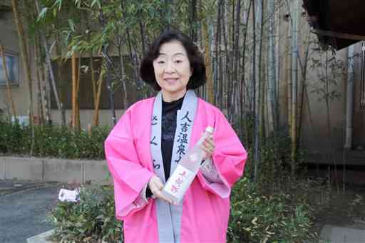 球磨焼酎「ひとよし女将桜」を持つさくら会会長の有村政代さん＝人吉市