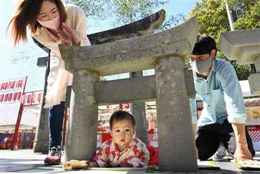 粟嶋神社の春季大祭で、ミニ鳥居をくぐる親子連れ＝宇土市