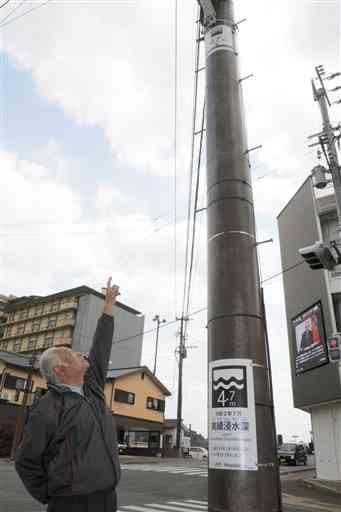 昨年７月の豪雨による浸水の高さを示す標識が設置された人吉市九日町の電柱。実際に水が達した位置と、通行人の目線の高さに２枚の標識で示している