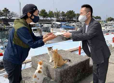 湯島の地域おこし協力隊の林愛子さん（左）に、ねこフェスでの募金を手渡すニューコ・ワンの塩原礼貴社長＝３月２９日、上天草市