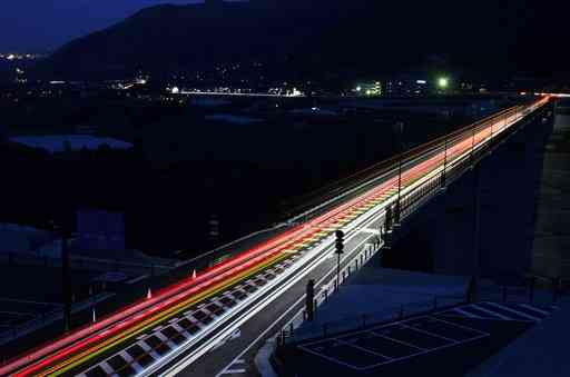 日が暮れてから、国道３２５号新阿蘇大橋を渡る車の光跡＝南阿蘇村