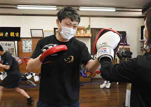 「吉田ボクシングジム　スタイルトップ」で会員のパンチをミットで受ける吉田龍生さん＝宇土市