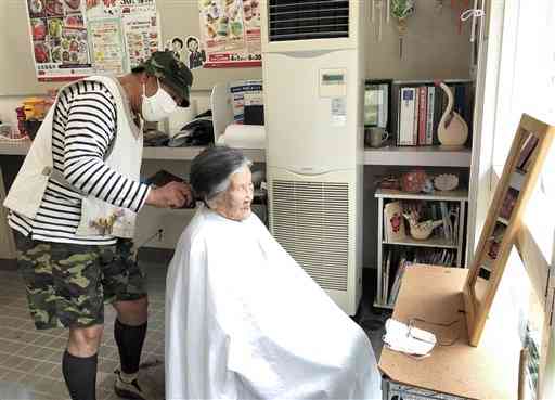 美容師の八木淳治さん（左）に髪を切ってもらう住民＝芦北町