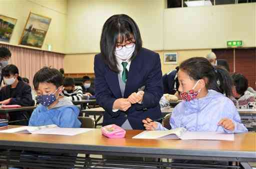 小国高生（中央）に教わりながら問題を解く児童ら＝南小国町