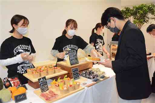 くまもと復興映画祭２０２１のスタッフ（右）に県産品を振る舞う熊本学園大の学生ら＝熊本市中央区