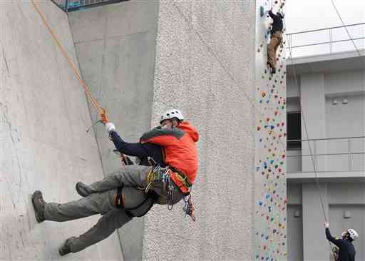 阿蘇署のクライミング施設で、岩場を想定して登る訓練をする県警の山岳救助隊員ら＝阿蘇市