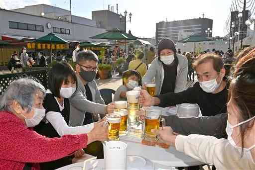 鶴屋百貨店屋上のビアガーデンがオープンし、マスクを着けたまま乾杯する来店客＝熊本市中央区（後藤仁孝）