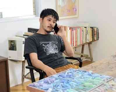 新しく構えたアトリエで、死にたいと訴える人からの相談電話を受ける作家の坂口恭平さん＝熊本市中央区