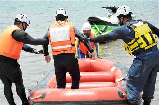県警の水難救助訓練で高齢者役の機動隊員をゴムボートに乗せる機動隊員ら＝１０日、嘉島町