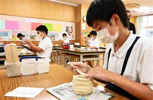 天草陶石が原料の粘土をカップなどの形に仕上げる児童たち＝天草市