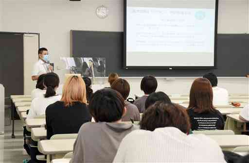 学生向け説明会で、ワクチン接種は任意であることを伝える與座嘉康・熊本保健科学大准教授（左奥）＝２８日、熊本市北区