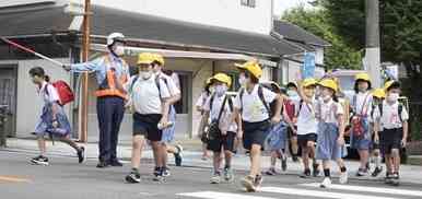 水俣署員に見守られながら下校する水俣第二小の子どもたち＝３０日、水俣市