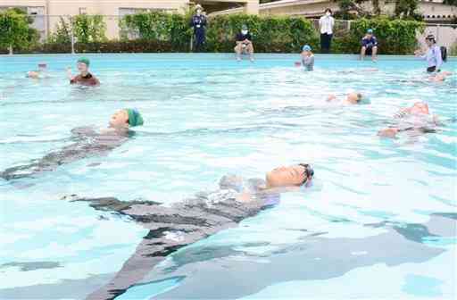 服を着たままで水に浮かぶ方法を学ぶ泗水西小の児童たち＝菊池市