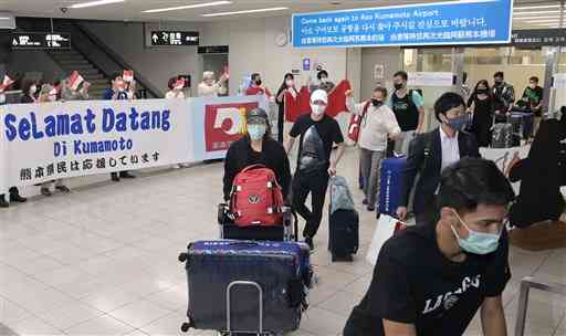 熊本空港に到着し、「ようこそ熊本へ」と書かれた横断幕で出迎えを受けるインドネシアのバドミントン代表チーム＝９日午後８時１０分ごろ、益城町（小野宏明）