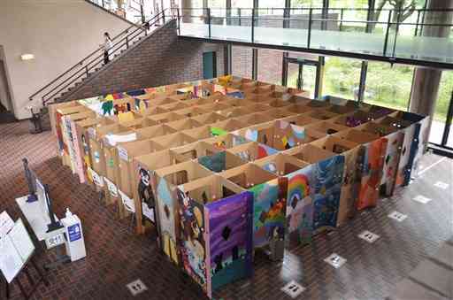 県内で美術を学ぶ高校生や大学生が壁画を制作した巨大段ボールの立体迷路。「迷路絵本展」の展覧会場外に設置されている＝熊本市中央区