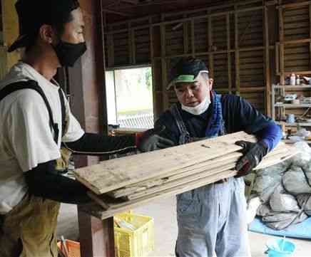 清掃を終えた住宅に木材を運び入れる五嶋章生さん（右）＝人吉市