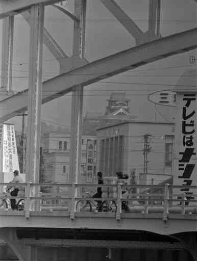 １９６２年３月、長六橋越しに見た熊本市街。中央に６０年に再建された熊本城の天守閣、左端に「熊本城再建記念・躍進熊本大博覧会」の看板が見える