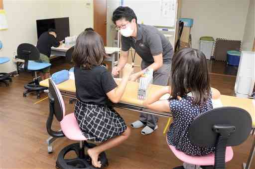 髪や瞳の色から受けるイメージについて子どもに尋ねる合志市地域おこし協力隊の安在渉さん＝同市