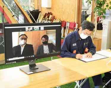 協定書に署名する松岡隼人市長（右）と、オンラインで出席したＷＯＮＤＥＲＷＯＯＤの坂口祐貴社長（中央）＝人吉市