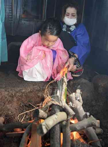 ご神体を温める火を準備する「火焚き乙女」の竹原千蘭ちゃん（左）と祖母の百合美さん＝阿蘇市