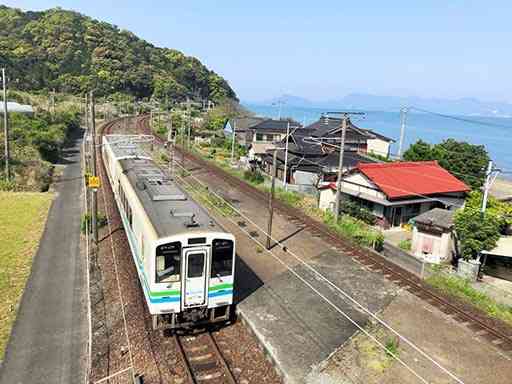 上田浦駅から写真奥の水俣方面に向かって出発する肥薩おれんじ鉄道の列車。フットパスのコースはしばらく線路沿いに続く