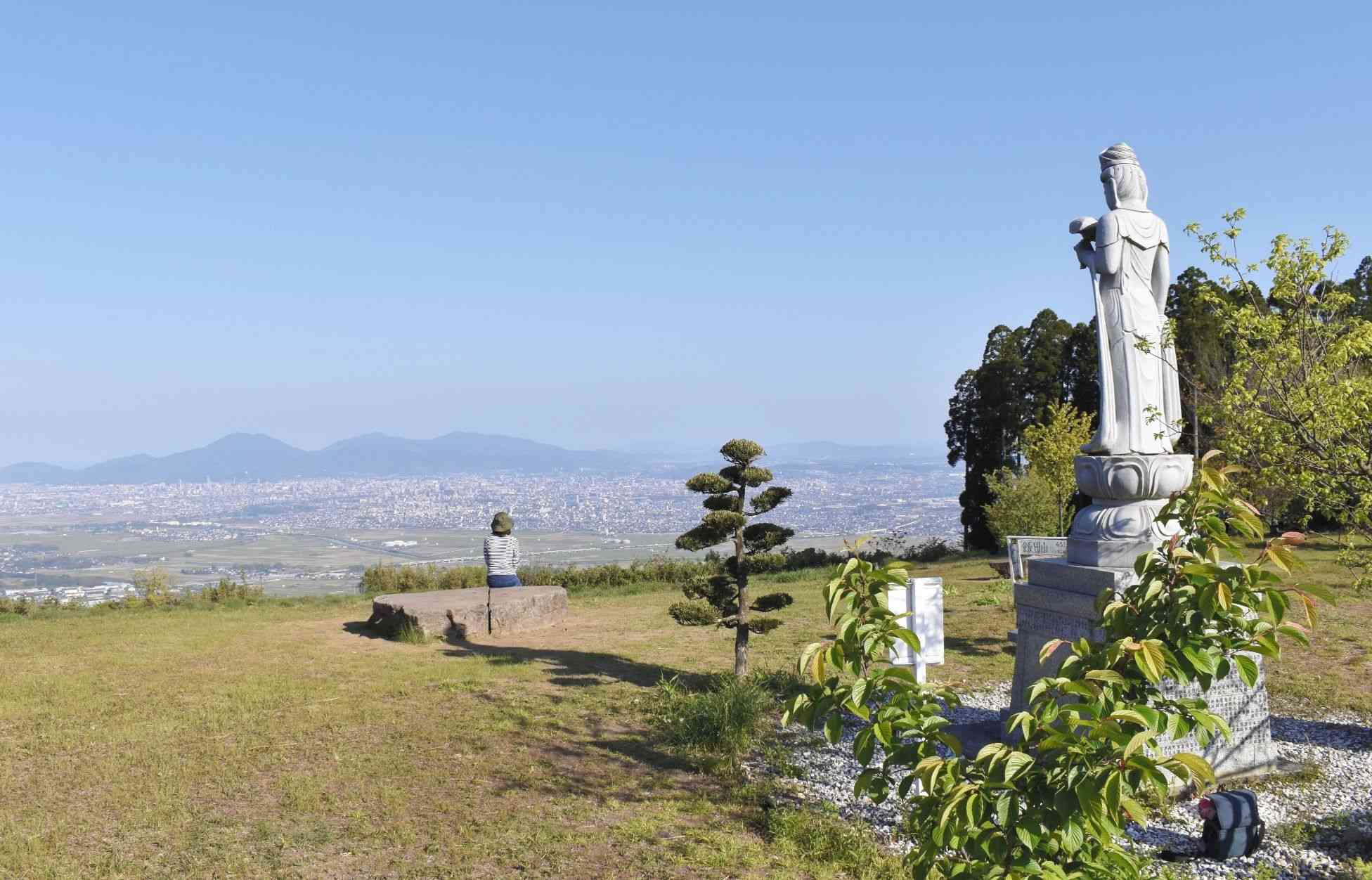 飯田山山頂自然公園から熊本市が一望。正面には金峰山系の山々が見える。山頂には観音像（右）も